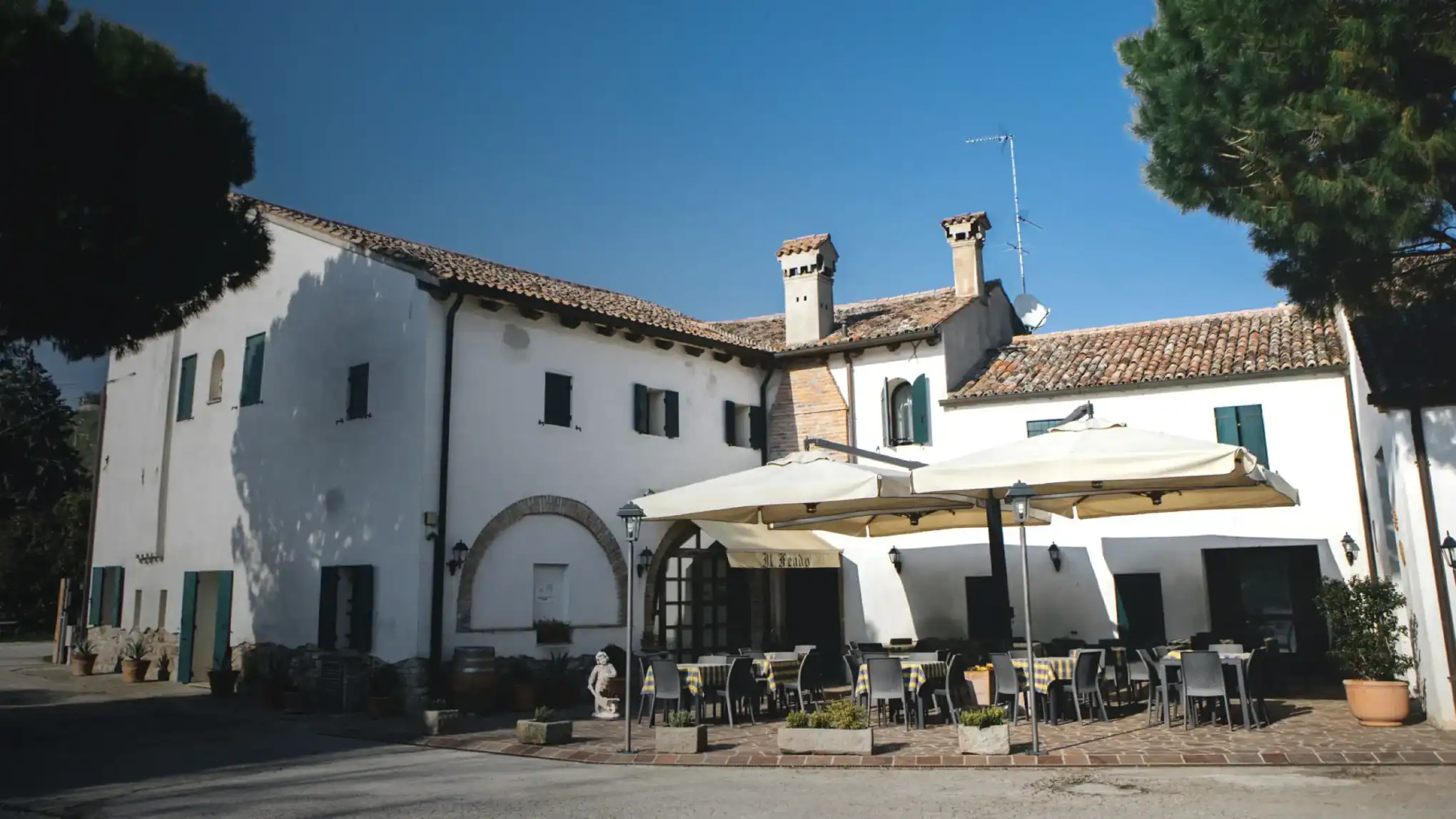 The farmhouse with its arched portico and terrace parasols