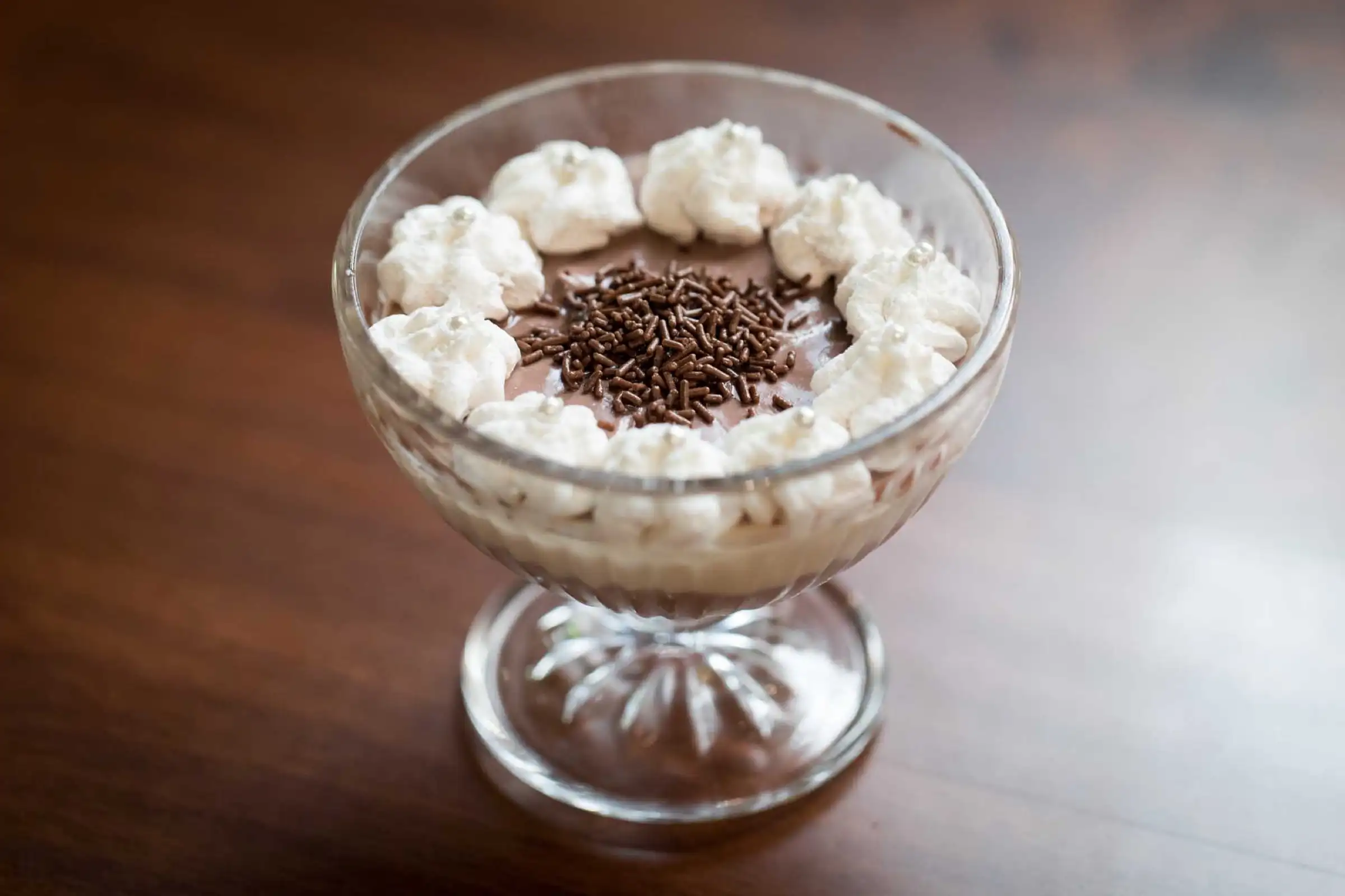 Spoon dessert in a glass cup with whipped cream