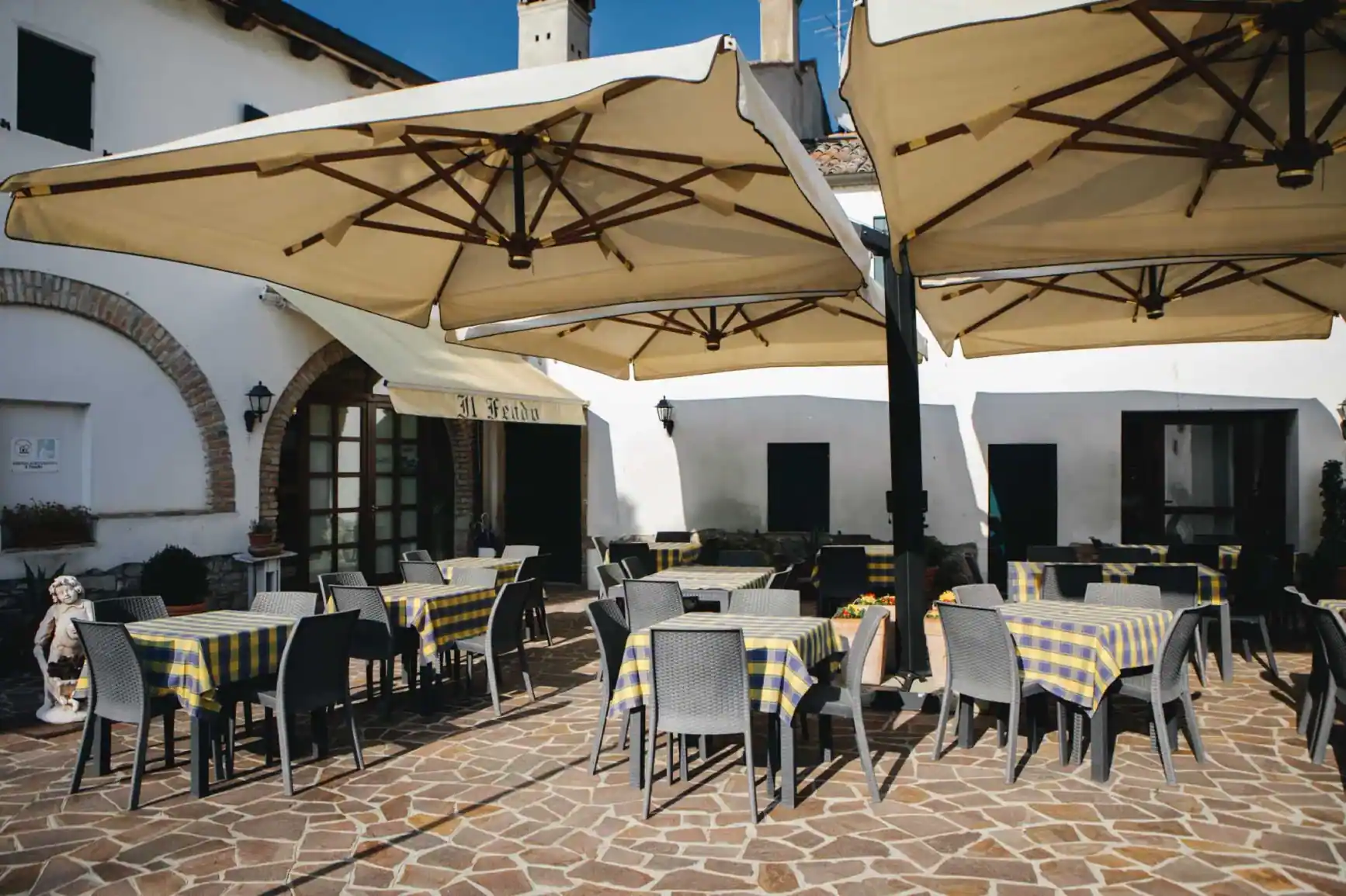 Die Sommerterrasse mit Tischen und großen Sonnenschirmen vor dem Landhaus