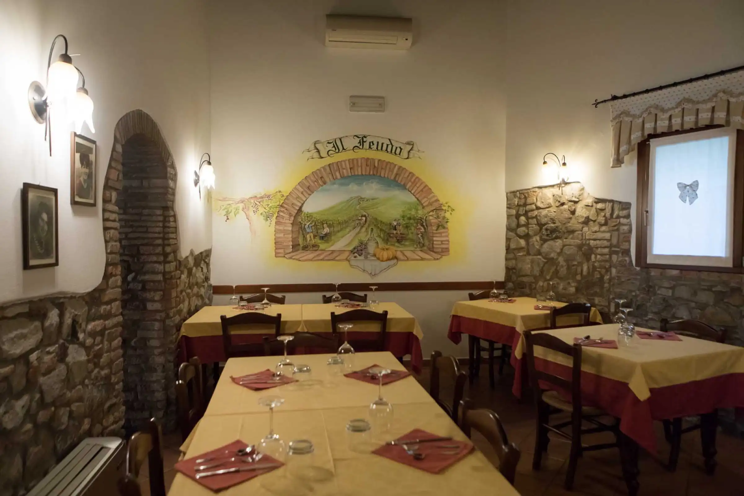 The dining room with the Il Feudo fresco and stone walls