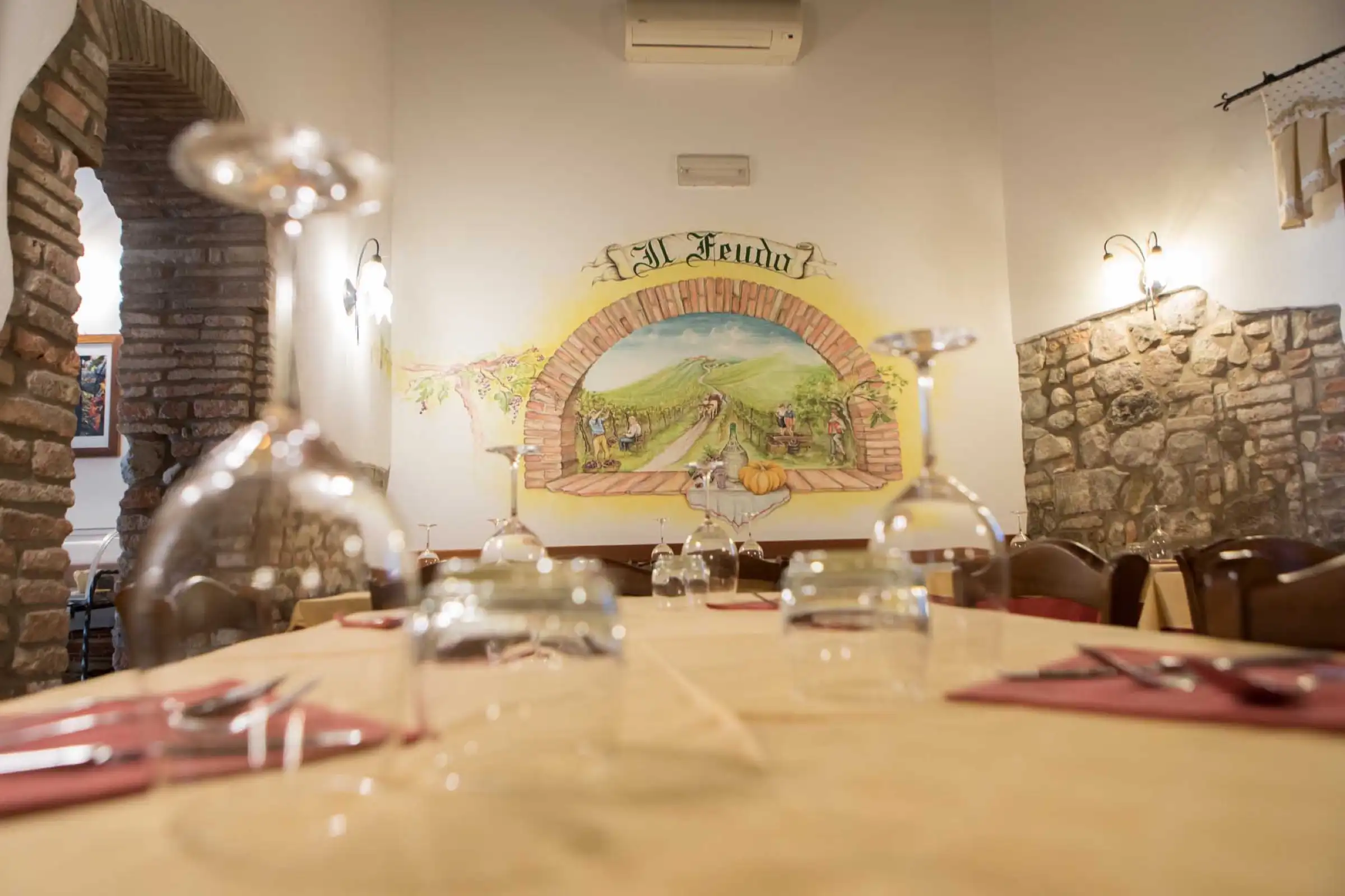 Gedeckter Tisch mit Weingläsern, im Hintergrund das Fresko der Weinlese