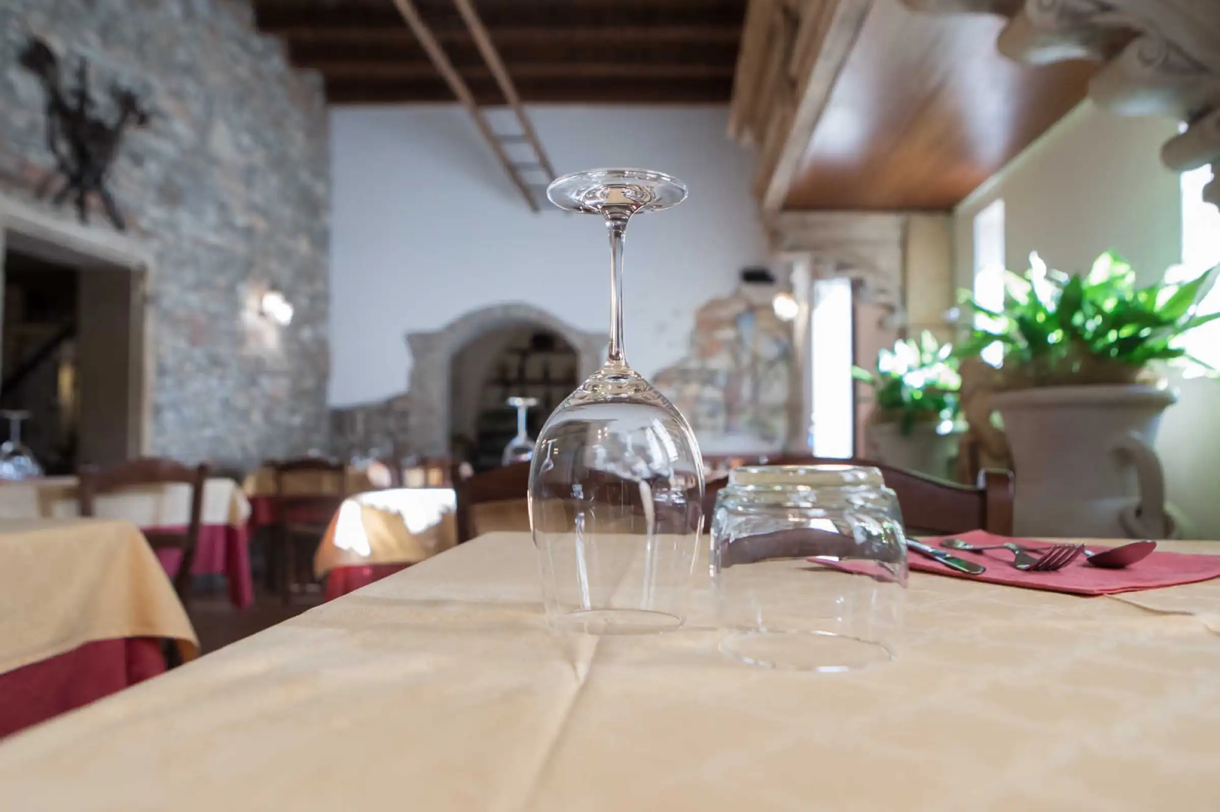 Upturned glasses on a laid table, with the dining room in the background