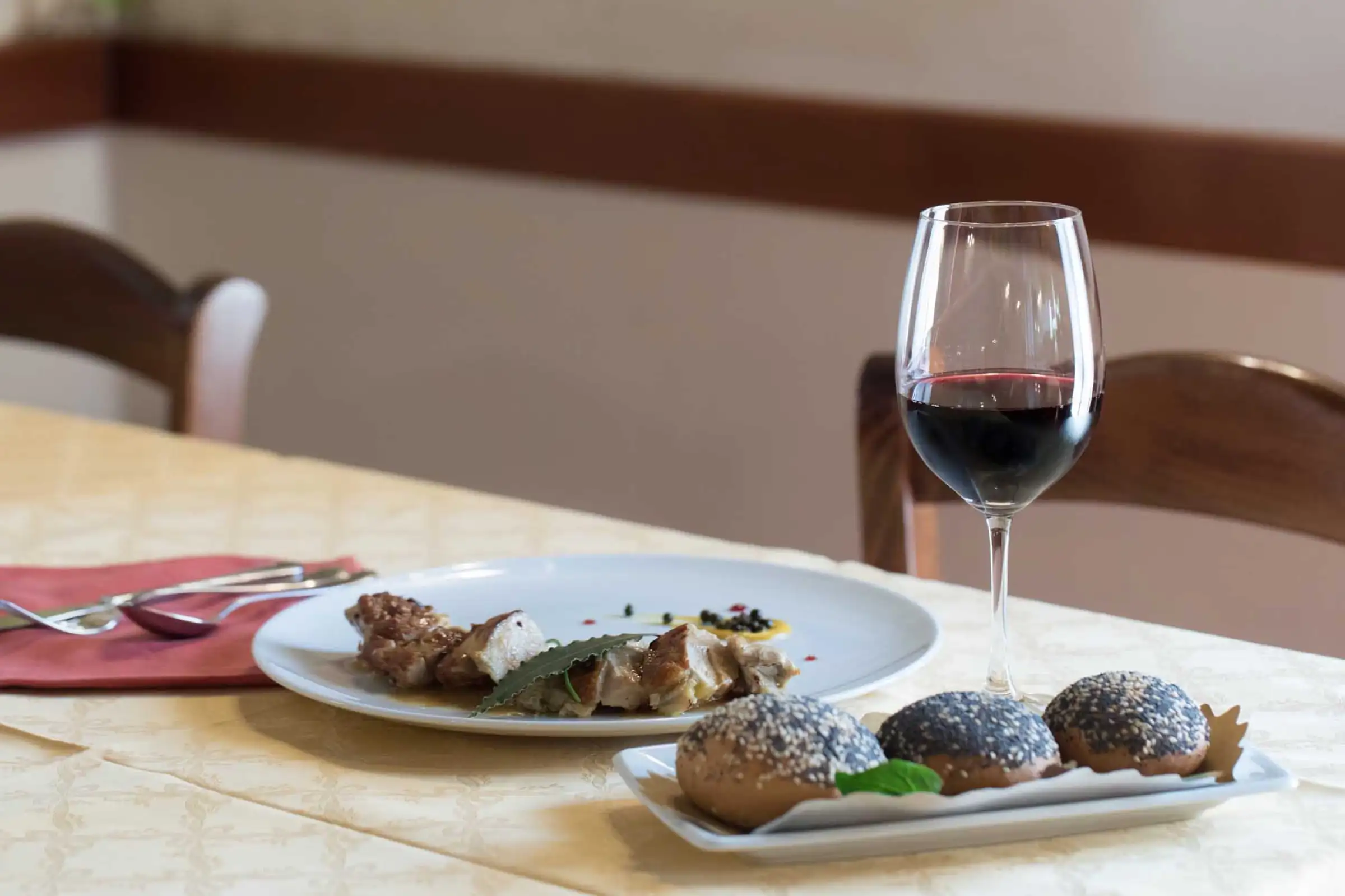 A glass of red wine next to house dishes on a laid table